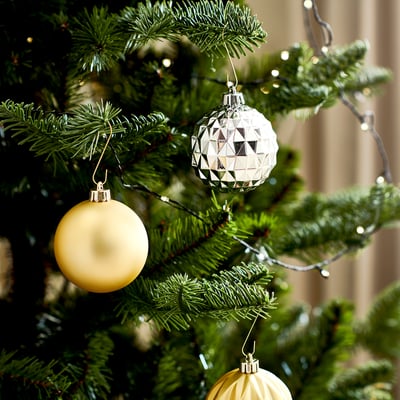 Christmas tree adorned with light-up ornaments, greenery, and yellow baubles.