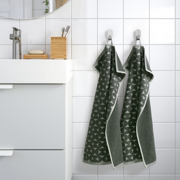 Two patterned bath towels hang on hooks near sink and mirror.