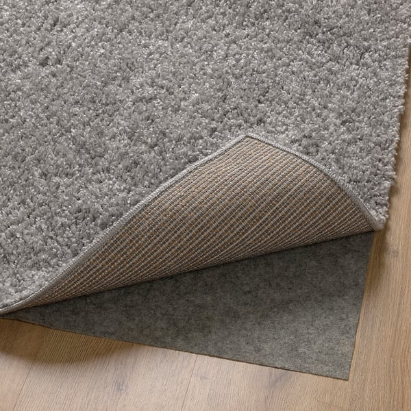 This image shows a rug with a soft, thick pile. The backing is visible, featuring a non-slip material, ensuring stability on wooden floors.