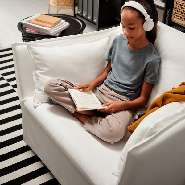 Girl reading in comfortable chair with headphones.