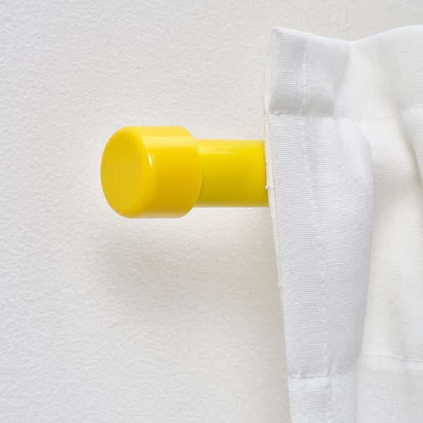 Bright yellow curtain rod finial holding white curtain, part of BEKRÄFTA set, attaches to wall for window dressing.