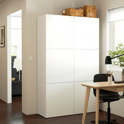 White BESTÅ storage unit with adjustable shelves, taller than desk, modern design, basket on top.