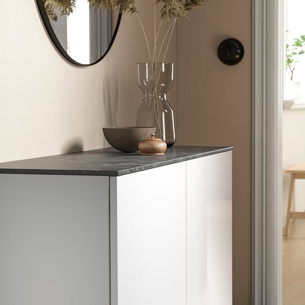 Modern console table with BESTÅ black marble top. Vase and bowl decor. Mirror above. Room visible in background.