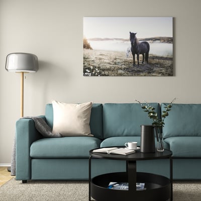 Turquoise sofa with pillows, black coffee table, potted plant. Above, canvas of horse in misty field.