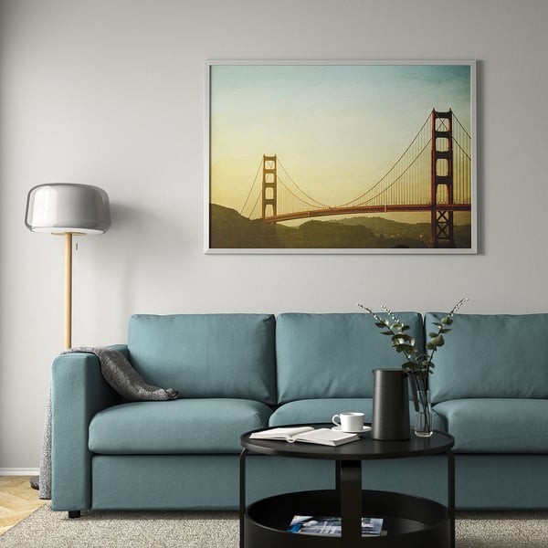 Modern living room with teal sofa, golden gate art, styled coffee table, and floor lamp.