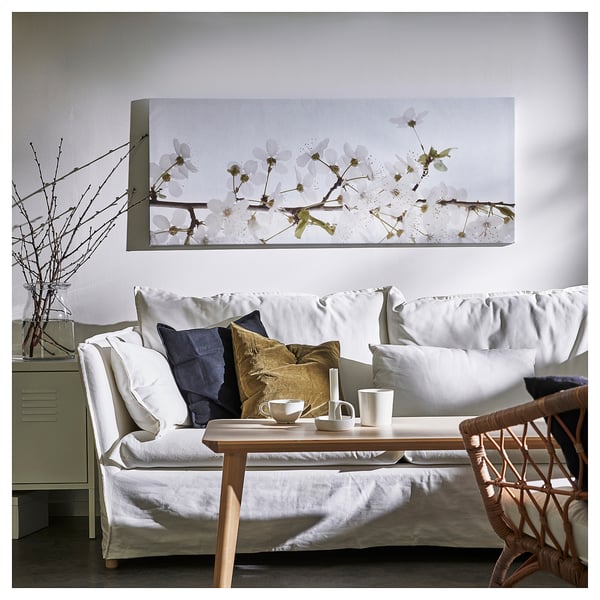 Modern living room with white sofa, cushions, table, and cherry blossom canvas art.
