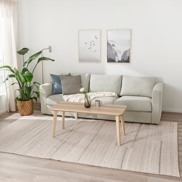 BRÖNDEN rug: cream wool carpet under sofa, minimalist living room.