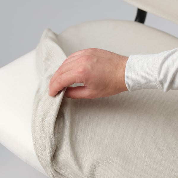 In a hand is shown adjusting a removable, washable chair cover, highlighting the products ease of cleaning and maintenance feature.