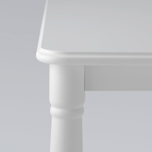 A close-up of a white tables corner showcasing smooth, rounded edges and sturdy metal leg joints.