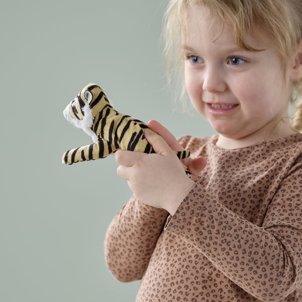Blonde girl, approximately two years old, holding a small plush tiger toy, smiling at the camera.