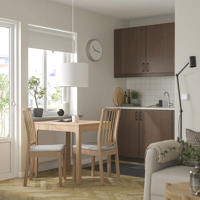 Modern kitchen with EKEDALEN table, chairs by window, seamless design, grey couch, dark cabinets.