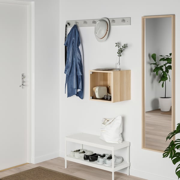 Organised entryway with white EKET cabinet, wooden shelf, hanging rail, mirror, and plants.
