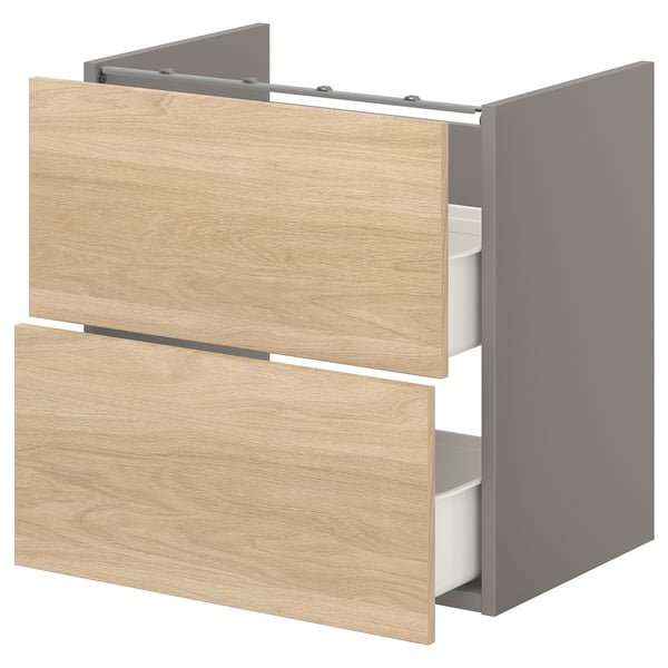 This image shows an ENHET bathroom cabinet in oak with two drawers. The cabinet is wooden with grey sides and open drawers revealing inner organisers.