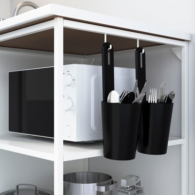 Kitchen shelf with microwave, hanging utensil caddies, pots, maintaining items visible and organised.