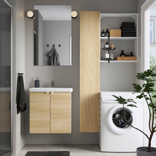 Modern bathroom: light oak cabinet, washing machine, glass shower, dark towels, circular lights, minimal sink.