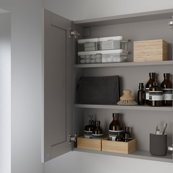 Open grey cabinet reveals organised bathroom essentials on shelves.