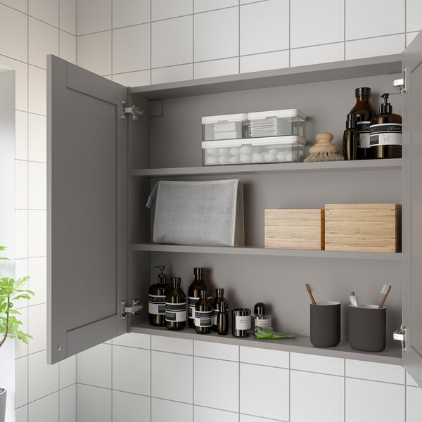 Open wall cabinet with mirror, storing bottles, cups, and organisers neatly. Grey frame matches ENHET series.