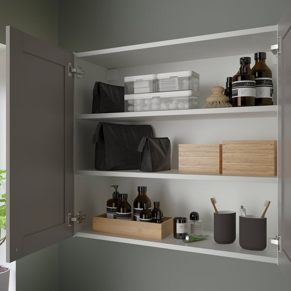 Open bathroom cabinet with shelves, holding various toiletries and storage boxes.