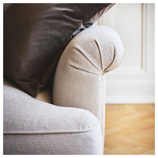 Close-up of ESSEBODA sofa, light grey, with a brown pillow, soft fabric, rounded armrests.