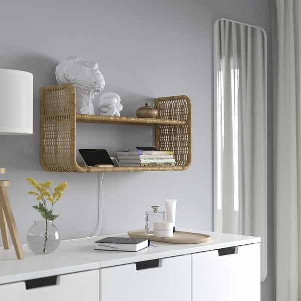 Wall-mounted wicker shelf holds towels, books, and phone. Rubber chargers through wall gap.