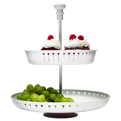 Two-tiered white serving stand with green grapes on bottom, two cupcakes with whipped cream and raspberries on top.