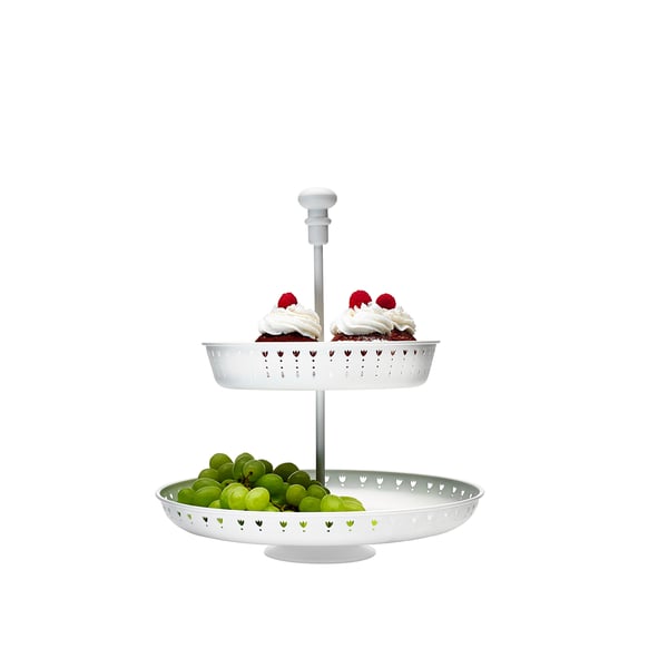 Tiered white serving stand holds two different foods, grapes on bottom, small cakes on top.