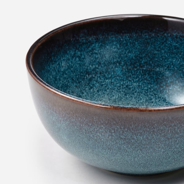 Close-up of elegant, handcrafted glazed bowl. Dark blue interior, golden rim. High-quality stoneware.