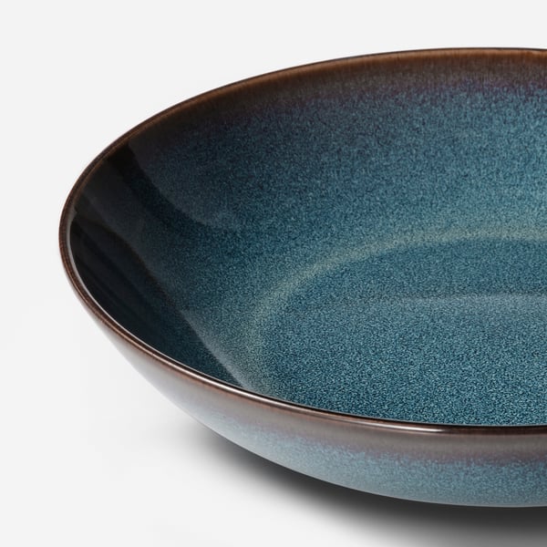 Deep plate in ocean-blue glaze with golden-brown rim; high-quality craftsmanship and elegant design.