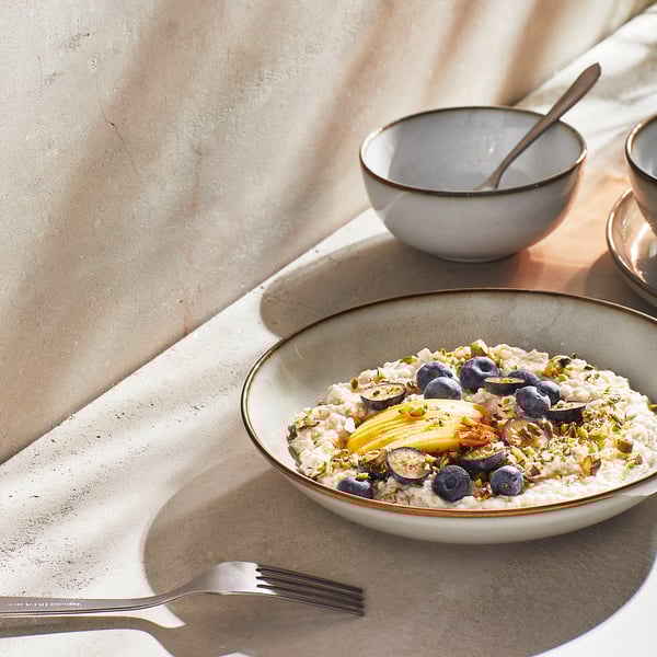 Sandy-colored plate with oats, blueberries, and fruit. Stoneware material, simple classic shape. Custom table setting design.