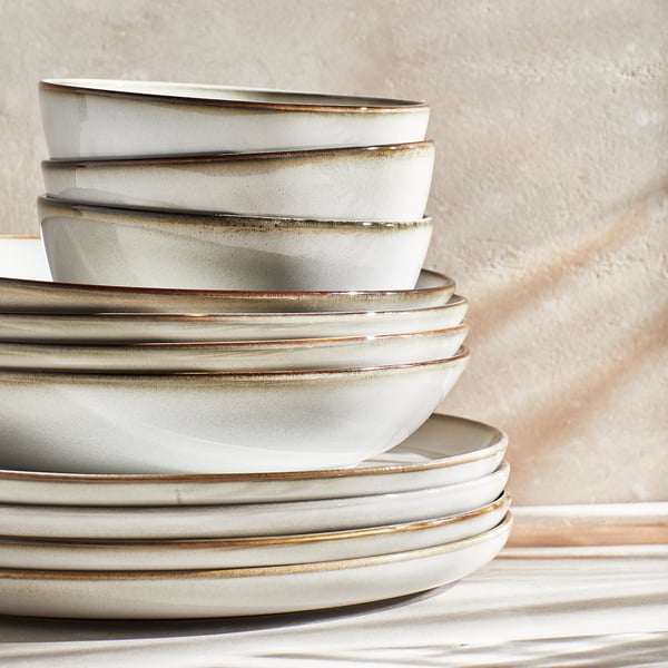 Stacked grey stoneware plates and bowls with sandy glaze texture and classic shape.
