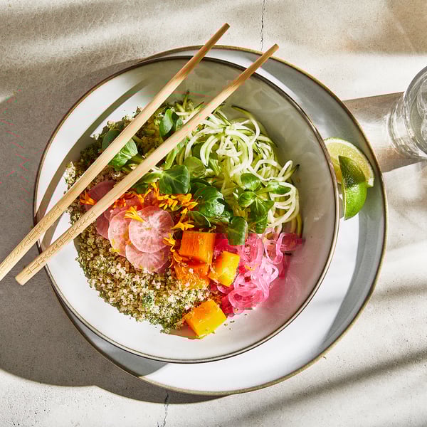 Large bowl with noodles, veggies, and chopsticks. Sand-glazed stoneware, rustic design.