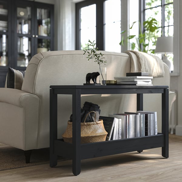 A cosy living room with a beige sofa, a dark wood HAVSTA console table displaying books and a plant.