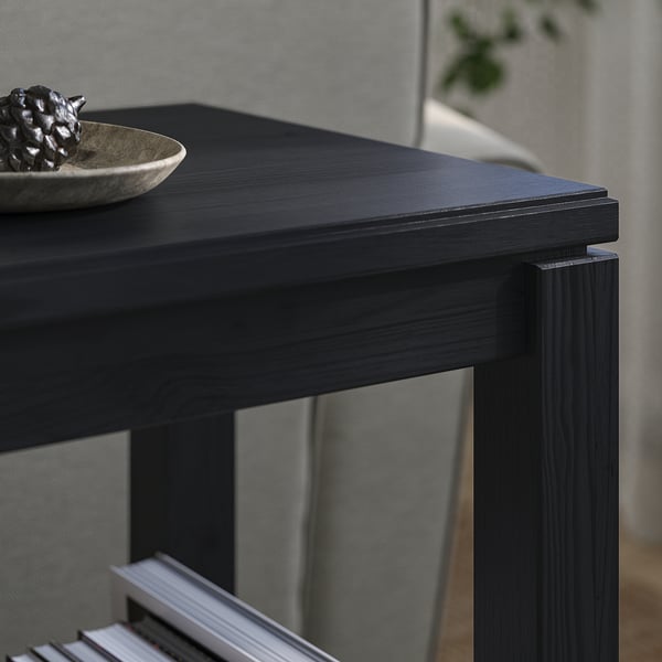 Black wooden console table with minimalist design, holding a bowl and decorative item, set against a grey wall.