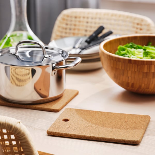 Kitchen counter with cork stands, saucepan, and vegetables.