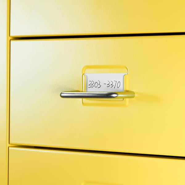 Yellow filing cabinet with metal handle and labelled slot.