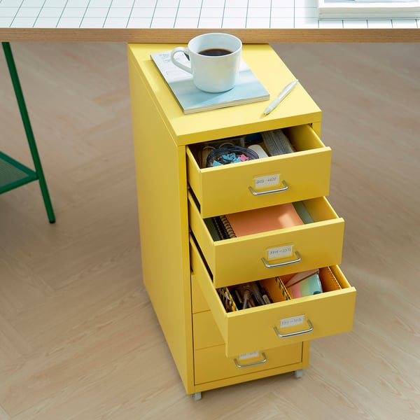 Yellow filing cabinet with 3 open drawers, cables, files. Near desk with notebook, compact for small spaces.