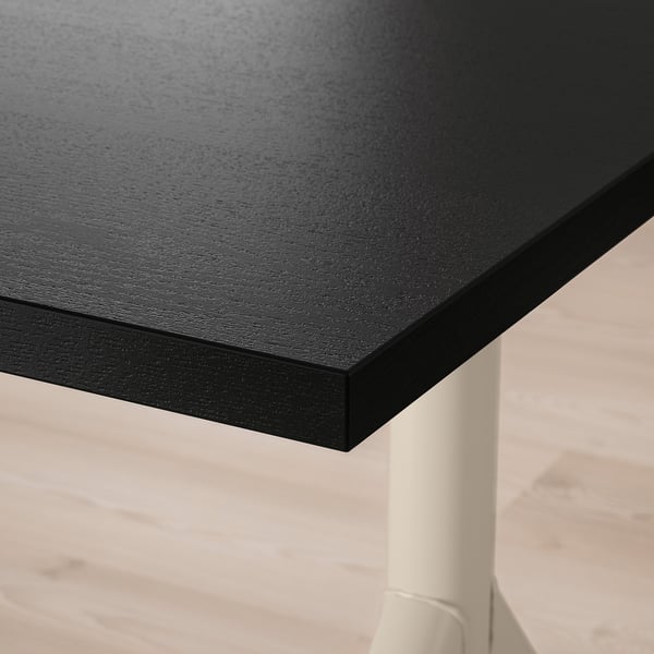 Close-up of sleek, black table surface, smooth and sturdy, supported by two white legs.