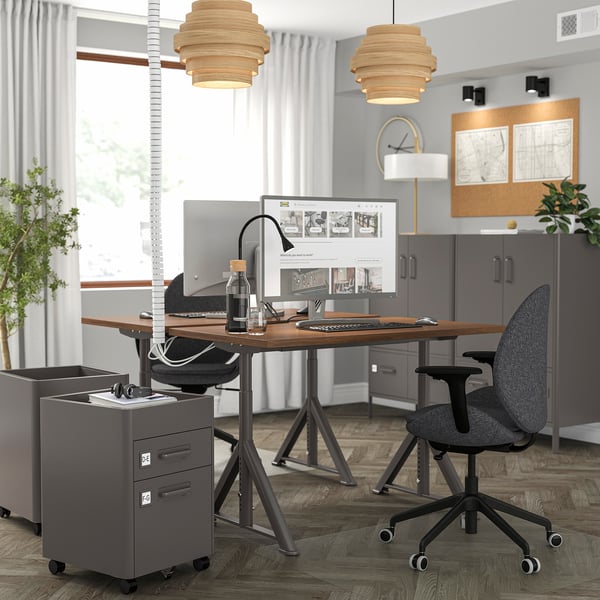 IDÅSEN desk setup with large monitor, laptop, chair, and file cabinet. Two pendants above.