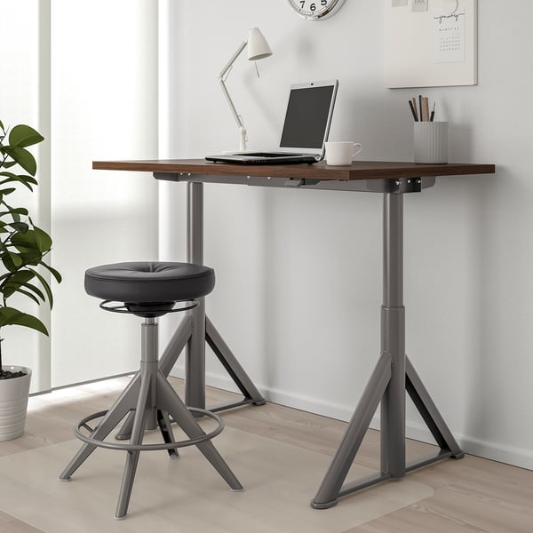 IDÅSEN standing desk in modern home office with adjustable stool, laptop, and decor.