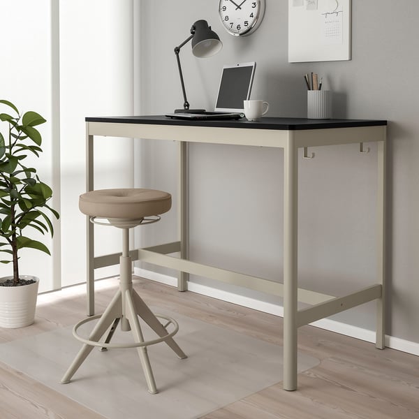Black & gold IDÅSEN desk with laptop, lamp, stool & plant. Stylish compact workspace.