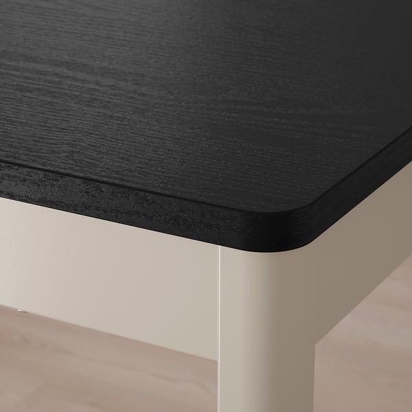 Close-up of modern black tabletop with sleek, rounded edges on a white base.