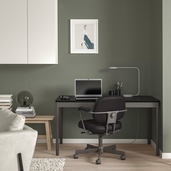 Modern home office with black IDÅSEN desk, laptop, chair, and decor.
