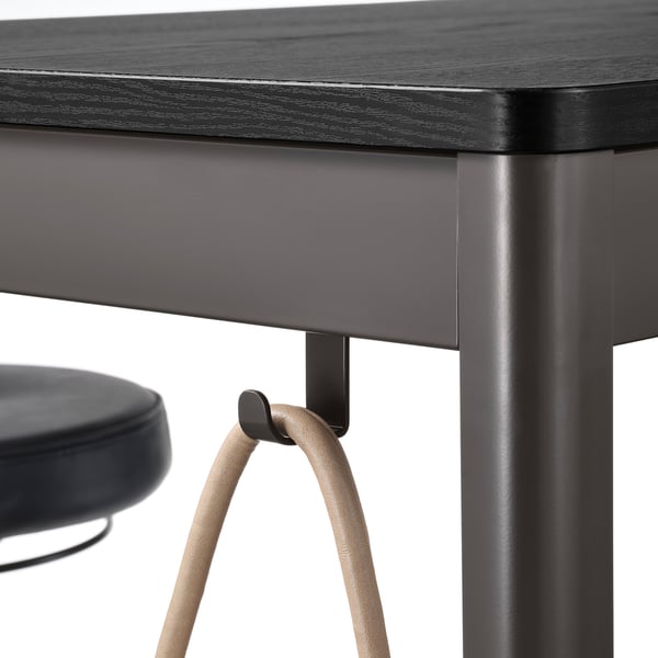 Close-up of modern table with hooked stool, grey wood top, metal base.