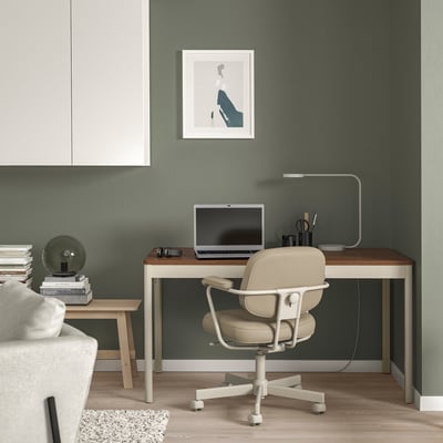 Modern home office with IDÅSEN desk, laptop, lamp, and chair. Green wall, art print, and shelf with books.