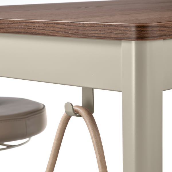 A close-up of a modern table with a wooden top and metallic legs, featuring a built-in hook for hanging items underneath.