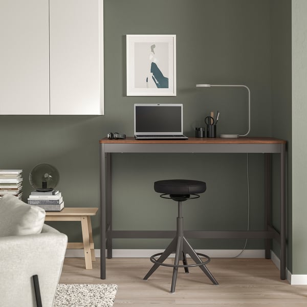 Modern dark grey IDÅSEN desk, smaller than main area items, with laptop, lamp, stool.