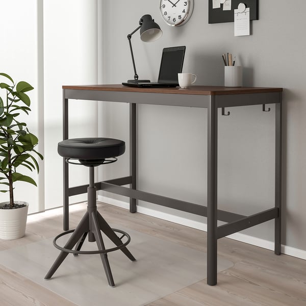 Black and wood IDÅSEN desk with stool against grey wall.