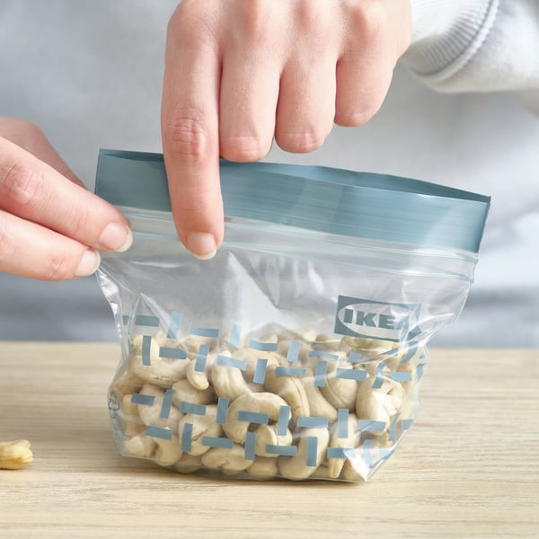 A transparent reusable storage bag being sealed, containing snacks, labelled IKEA.