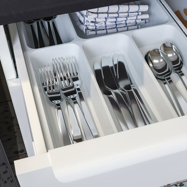 Utensil drawer with compartments: forks, knives, spoons, neatly organised.