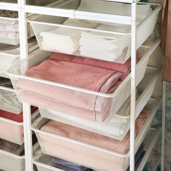 White mesh storage baskets organise pink towels on a shelf system, ideal for tidy spaces.